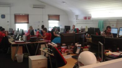 Office workers collaborate around a table as charts suggest steady business growth.